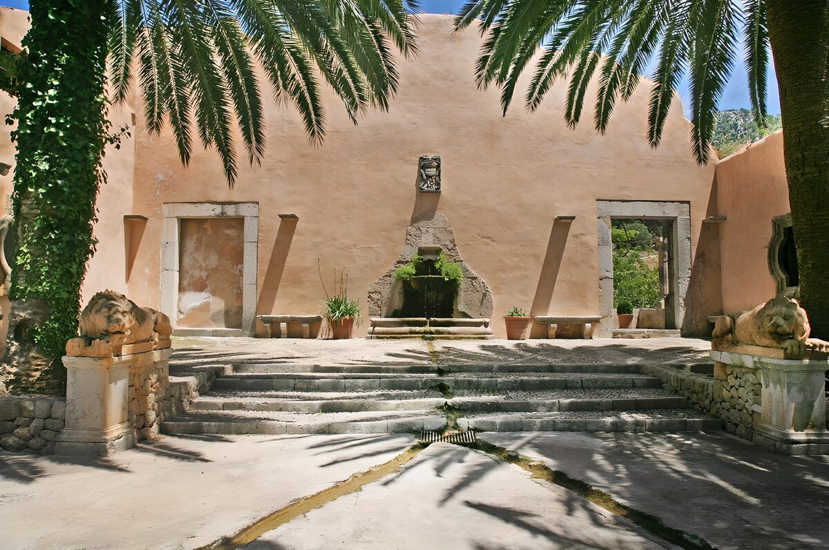 View towards orangy wall with fountain , palm trees and statues
